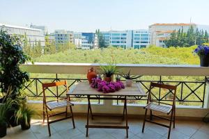CASA MYRlAM Marousi -View & Private Parking- في أثينا: طاولة على شرفة مع الزهور عليها