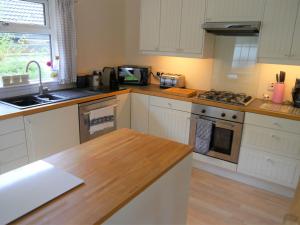 a kitchen with white cabinets and a wooden counter top at Arakhova in Kirkcudbright