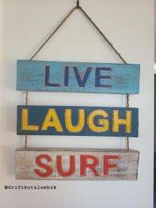 a sign that says love laugh supreme hanging on a wall at Drift Hideaway in Kuta Lombok