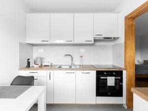 eine Küche mit weißen Schränken und einem Waschbecken in der Unterkunft Apartma Vrtnica 5th floor in Nova Gorica