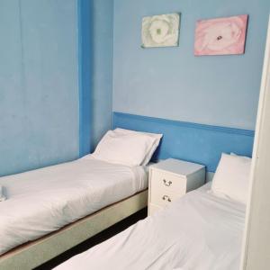 2 camas individuales en una habitación con paredes azules en The New Osterley Hotel, en Blackpool