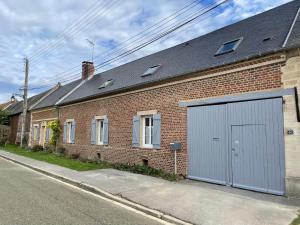 ein Backsteingebäude mit einer Garage auf einer Straße in der Unterkunft Confortable duplex au cœur de la campagne Picarde à 1h de Paris in Biermont