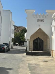 un edificio con una puerta negra en un estacionamiento en old muscat en Mascate