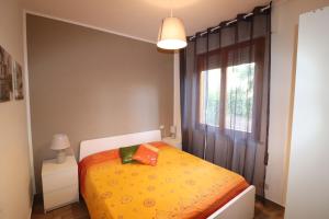 una camera da letto con un letto con una coperta gialla e una finestra di Appartamenti Tahiti a Follonica