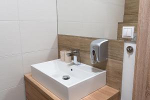 ein Badezimmer mit einem weißen Waschbecken und einem Spiegel in der Unterkunft Penzión ** Kolkáreň in Vyhne