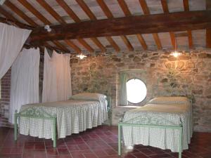 Agriturismo Le Vigne di Pace في أمبيرتيدي: سريرين في غرفة بجدار حجري
