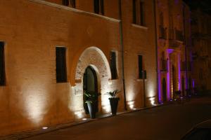 a building with an arch and two plants in a street at Domus Mariae Benessere in Siracusa