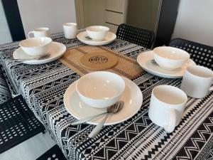 a table with white cups and saucers on it at Jesselton Quay,2BR,4-5pax,Mountain view in Kota Kinabalu