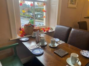 una mesa con platos y tazas y una cesta en ella en Talbot House Bed & Breakfast and Tearoom en Pateley Bridge