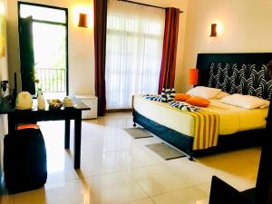 a bedroom with a bed and a table and a window at Flower Garden Eco Village in Sigiriya