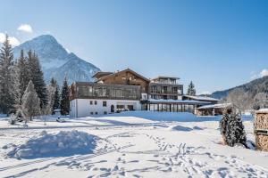a resort in the snow with a mountain in the background at Hotel Fischer am See in Heiterwang