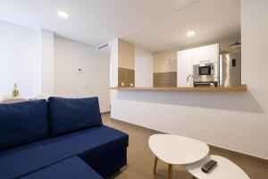 a living room with a blue couch and a kitchen at Jardines Iro in Chiclana de la Frontera