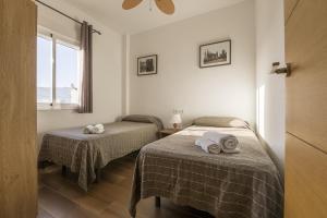 two beds in a room with a window at Duplex Near the Beach in Chiclana de la Frontera +20 photos