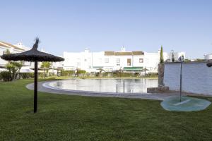 an umbrella sitting in the grass next to a pool at Duplex Near the Beach in Chiclana de la Frontera