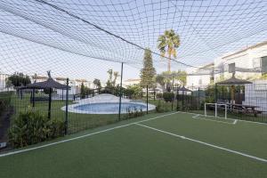a tennis court in front of a house with a tennis court at Duplex Near the Beach in Chiclana de la Frontera