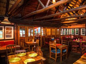 Malandela's Guest House في Malkerns: مطعم بطاولات وكراسي خشبية ونوافذ