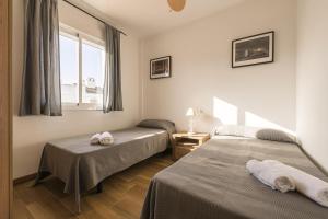 two beds in a room with a window and two towels at Beautiful Duplex in Chiclana de la Frontera +23 photos