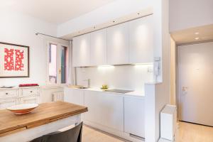 una cucina con armadi bianchi e tavolo in legno di Padova Centre Cosy Apartment a Padova