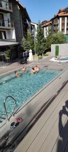 three people are swimming in a swimming pool at Bansko Luxury apartment in St Ivan Rilski Spa 4 Bansko Private SPA & Minreal Hot water pools in Bansko