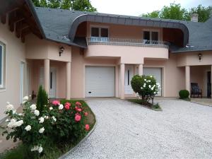 a house with a driveway and flowers in front of it at Castelinho Apartmanház in Gyenesdiás