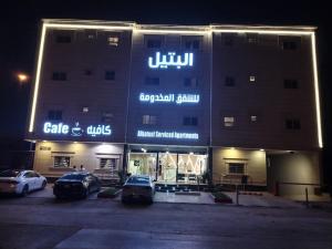 un grand bâtiment avec des voitures garées dans un parking dans l'établissement Al Bateel Furnished Apartments, à Riyad