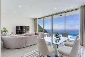 een woonkamer met een bank, een tafel en stoelen bij Luxury Villa Bianca by Holiday Rental Madeira in Arco da Calheta