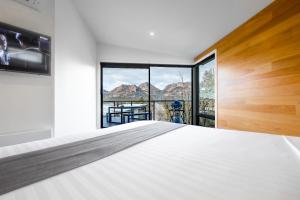 ein Schlafzimmer mit einem Bett und einem großen Fenster in der Unterkunft At The Bay in Coles Bay
