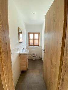 a bathroom with a sink and a toilet and a window at Ferienwohnungen Heillinger Gütl in Ruhpolding