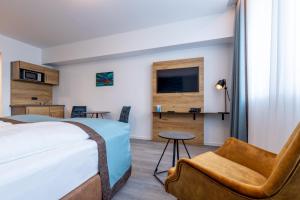 エッセンにあるTrip Inn Hotel & Suites Essenのベッドと椅子付きのホテルルーム