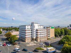 a large white building in a city with a parking lot at Trip Inn Hotel & Suites Essen in Essen