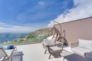 Un balcón con sillas y vista a una ciudad. en Luxury Villa Bianca by Holiday Rental Madeira, en Arco da Calheta