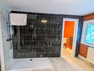 a bathroom with a shower with a black tile wall at Kaoglen Doe-Feature Bathroom-Cairngorms-Pets Allowed in Balnald