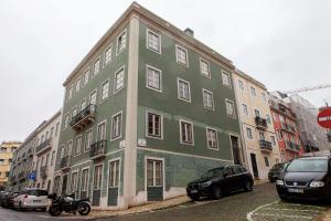 un bâtiment vert avec des voitures garées devant lui dans l'établissement Charming 2BDR Apartment in Lapa by LovelyStay, à Lisbonne