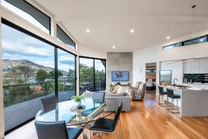 a living room with a glass table and chairs and a kitchen at At The Bay in Coles Bay