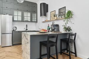 a kitchen with black cabinets and a counter with stools at Family Apartment - 74m2 - Wapienna by Renters in Wrocław