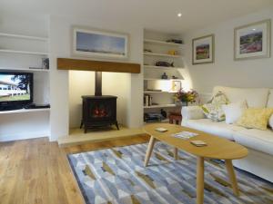 a living room with a white couch and a fireplace at Fiddlesticks Cottage in Beaminster
