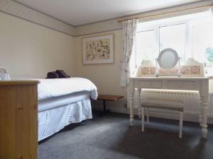 a bedroom with a bed and a mirror and a window at Fiddlesticks Cottage in Beaminster