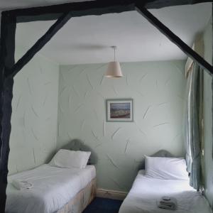 Dos camas en una habitación con paredes blancas. en The New Osterley Hotel, en Blackpool