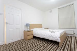 a white bedroom with a bed and a door at Brown house in Leeds in Leeds