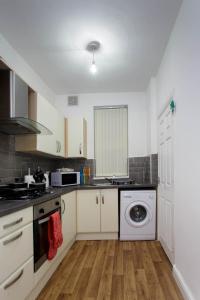 a kitchen with white cabinets and a washing machine at Brown house in Leeds in Leeds