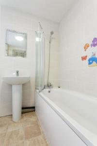 Brown house in Leeds في ليدز: حمام أبيض مع حوض وحوض ومغسلة