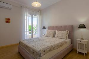a white bedroom with a bed and a window at The Bright Suite in Corfu