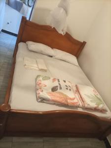 uma cama com uma cabeceira de madeira com um cobertor em Pearl Motel Buloba em Buloba