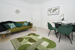 a living room with a green couch and a table at Beautiful 3-Bed House by MiniStays Stoke-on-Trent in Stoke on Trent