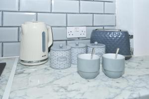 a kitchen counter with four cups and a blender at Beautiful 3-Bed House by MiniStays Stoke-on-Trent in Stoke on Trent