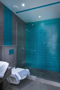 e bagno piastrellato blu con doccia e servizi igienici. di El Mare Seaside Retreats - Bespoke Luxury Getaways a Limenaria