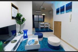 民宿　setouchi في تاكاماتسو: غرفة معيشة مع كراسي زرقاء وطاولة