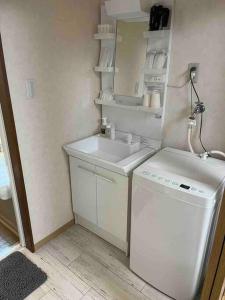 uma pequena cozinha com um lavatório e uma máquina de lavar roupa em 民宿　setouchi em Takamatsu