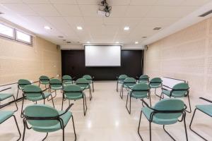 una sala de conferencias con sillas verdes y una pantalla en Albergue Inturjoven Chipiona, en Chipiona