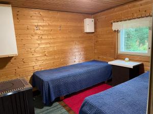 two beds in a room with wooden walls and a window at Villa Mushroom in Vuoriniemi